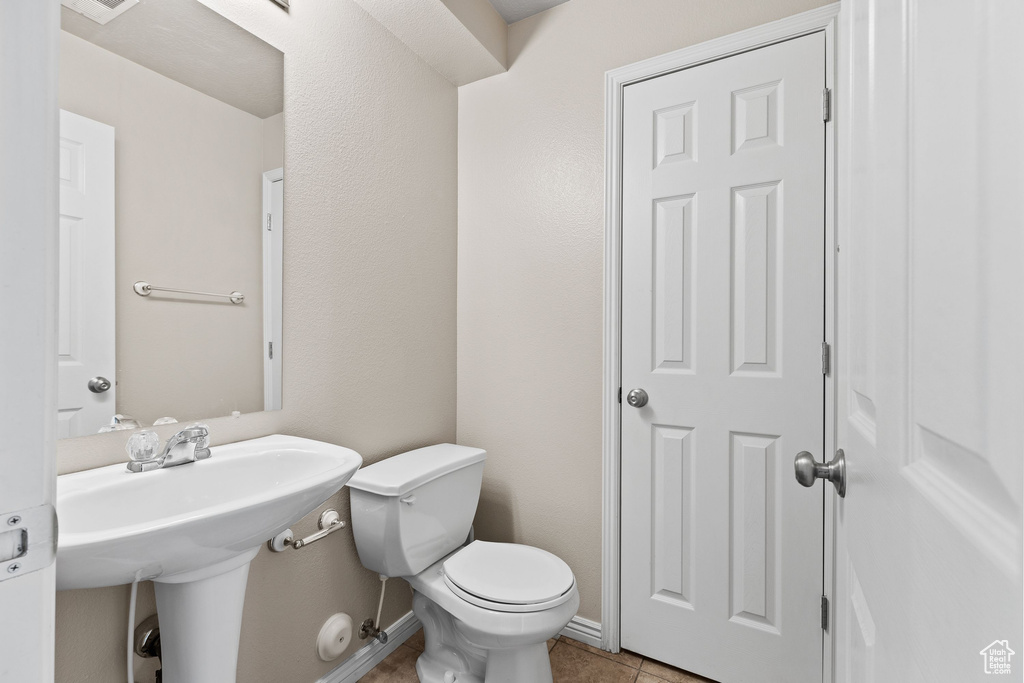 Half bath featuring toilet, tile patterned floors, and baseboards