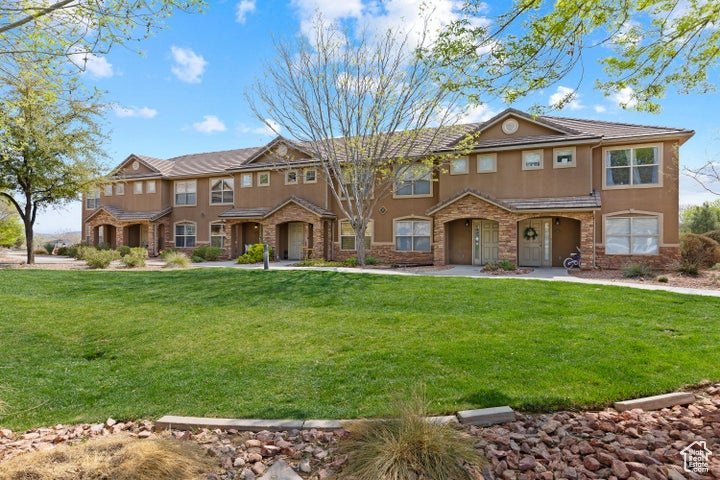 View of front of house featuring stucco siding, stone siding, and a front lawn