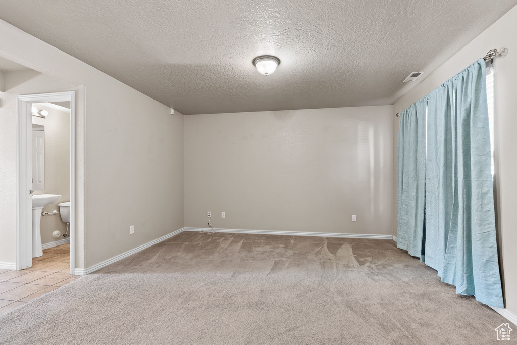 Carpeted empty room featuring a textured ceiling and baseboards