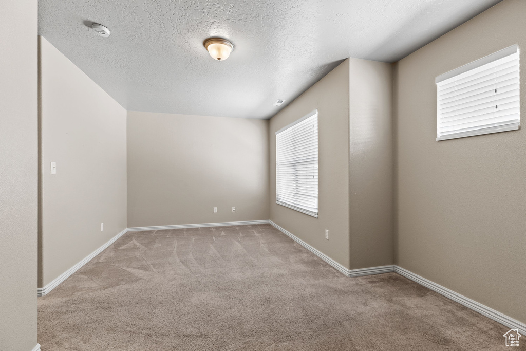Spare room with carpet, baseboards, a textured ceiling, and a smoke detector