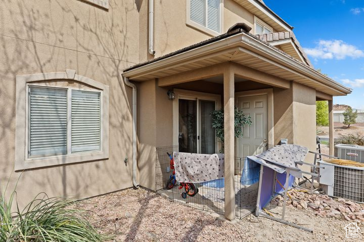 Entrance to property with stucco siding and cooling unit