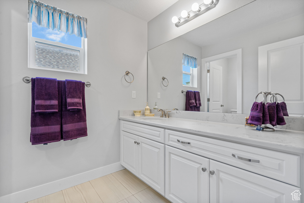 Bathroom with baseboards, vanity, and tile patterned flooring