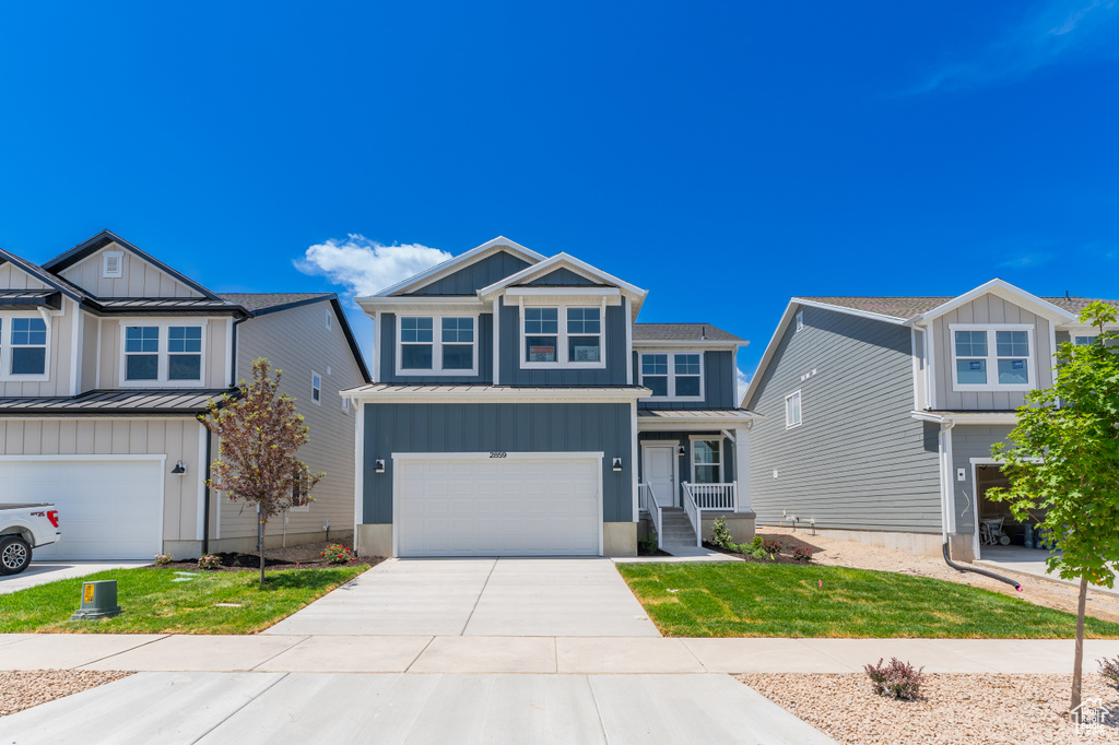 Craftsman-style home with a standing seam roof, board and batten siding, a garage, driveway, and metal roof