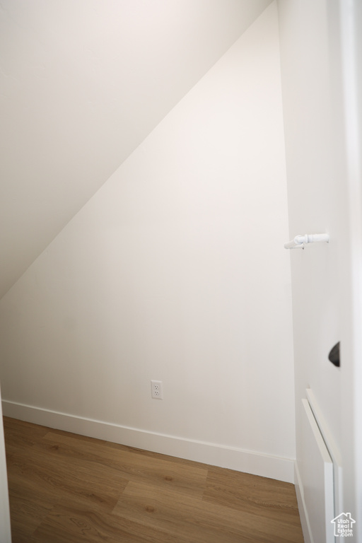 Additional living space featuring radiator heating unit, lofted ceiling, baseboards, and light wood finished floors