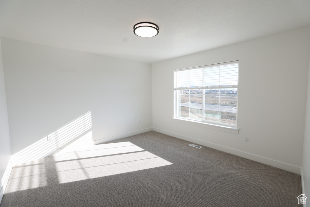 Carpeted spare room with baseboards and visible vents