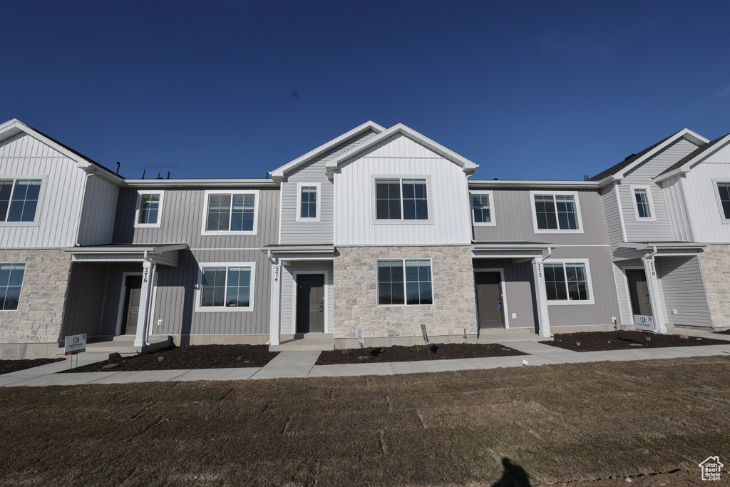 View of property with a front yard and stone siding