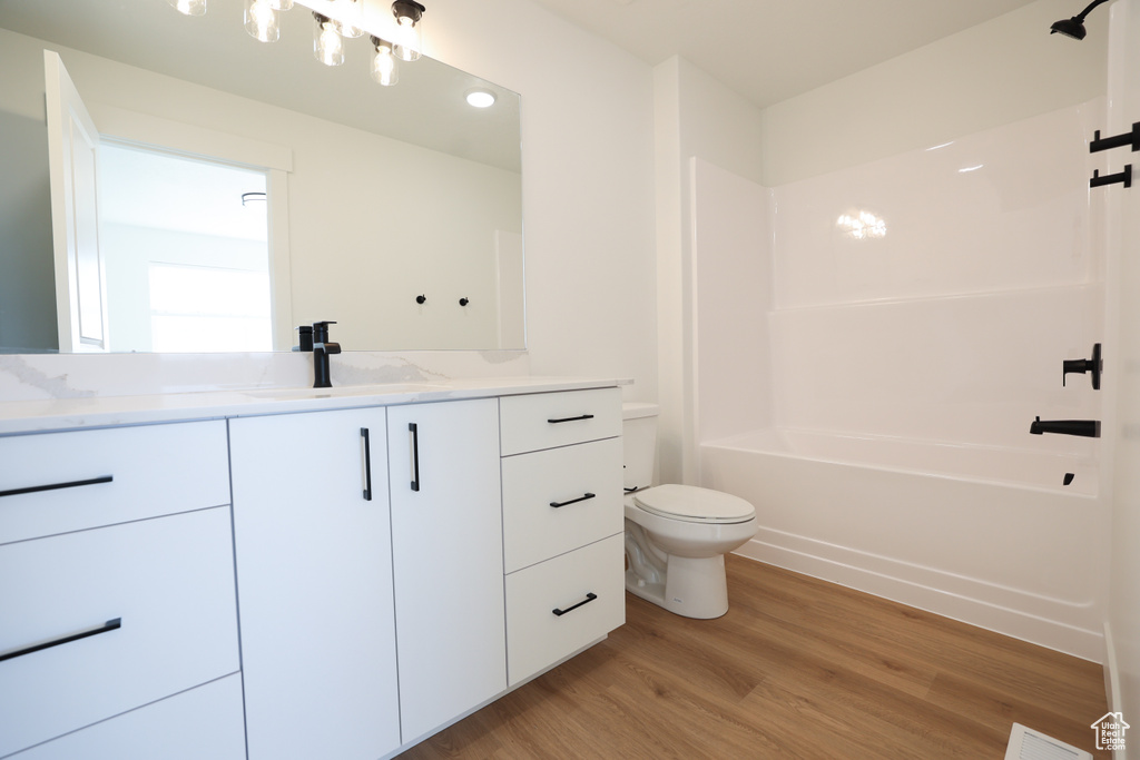 Bathroom with bathing tub / shower combination, toilet, vanity, and wood finished floors