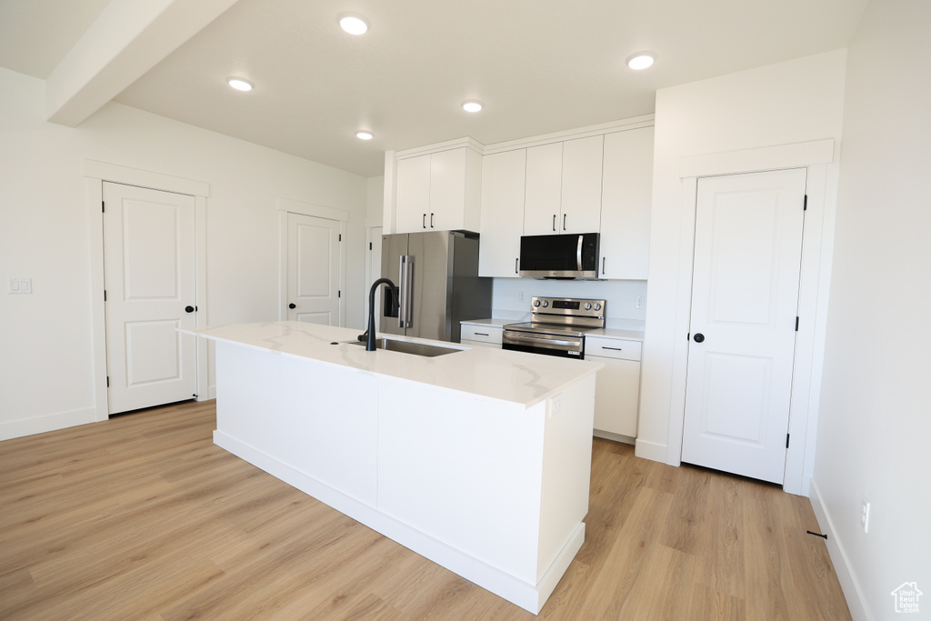 Kitchen with white cabinetry, light wood-style flooring, a sink, and stainless steel appliances