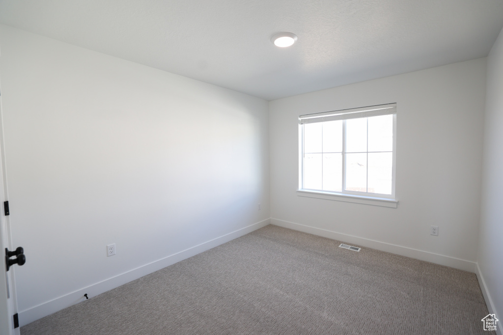 Spare room with light colored carpet, visible vents, and baseboards