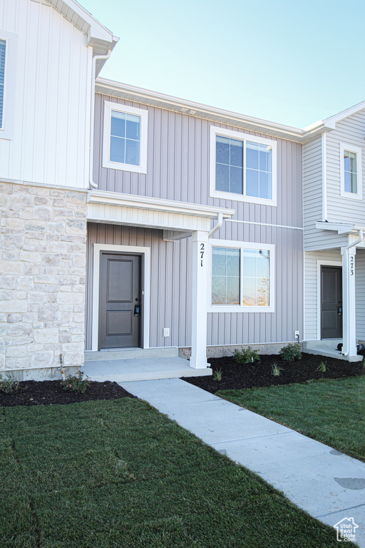 View of front of home with stone siding, board and batten siding, and a front yard