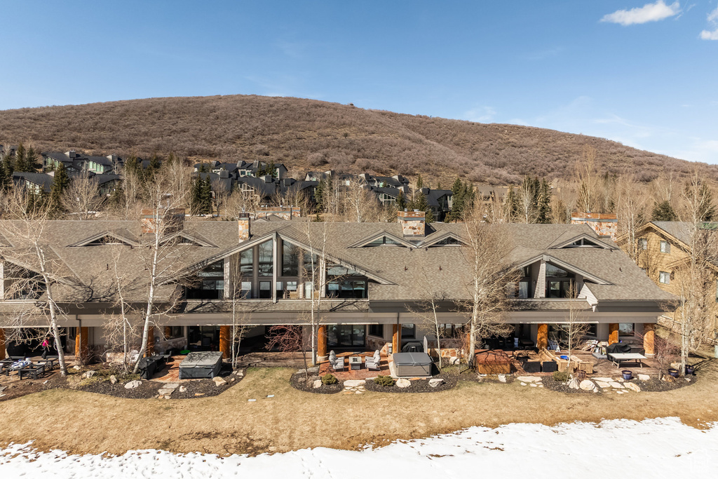 Rear view of property featuring a residential view, a shingled roof, a patio area, and a mountain view