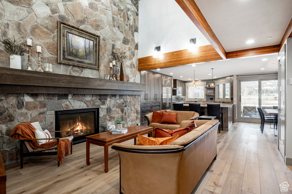 Living area featuring beamed ceiling, a fireplace, and light wood-type flooring