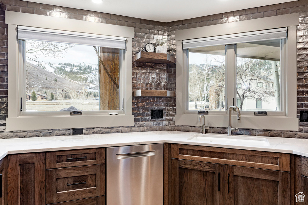 Kitchen featuring a sink, stainless steel dishwasher, and light stone counters