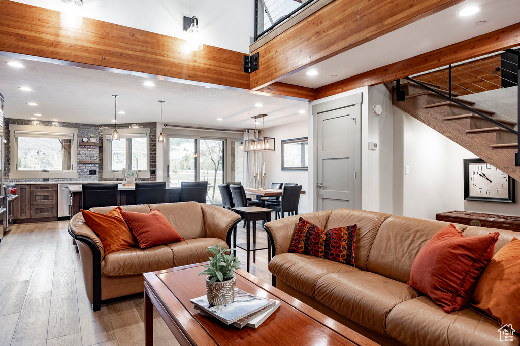 Living room with stairs, beamed ceiling, light wood-style flooring, and recessed lighting