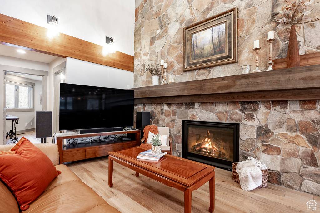 Living area featuring a high ceiling, a stone fireplace, and wood finished floors