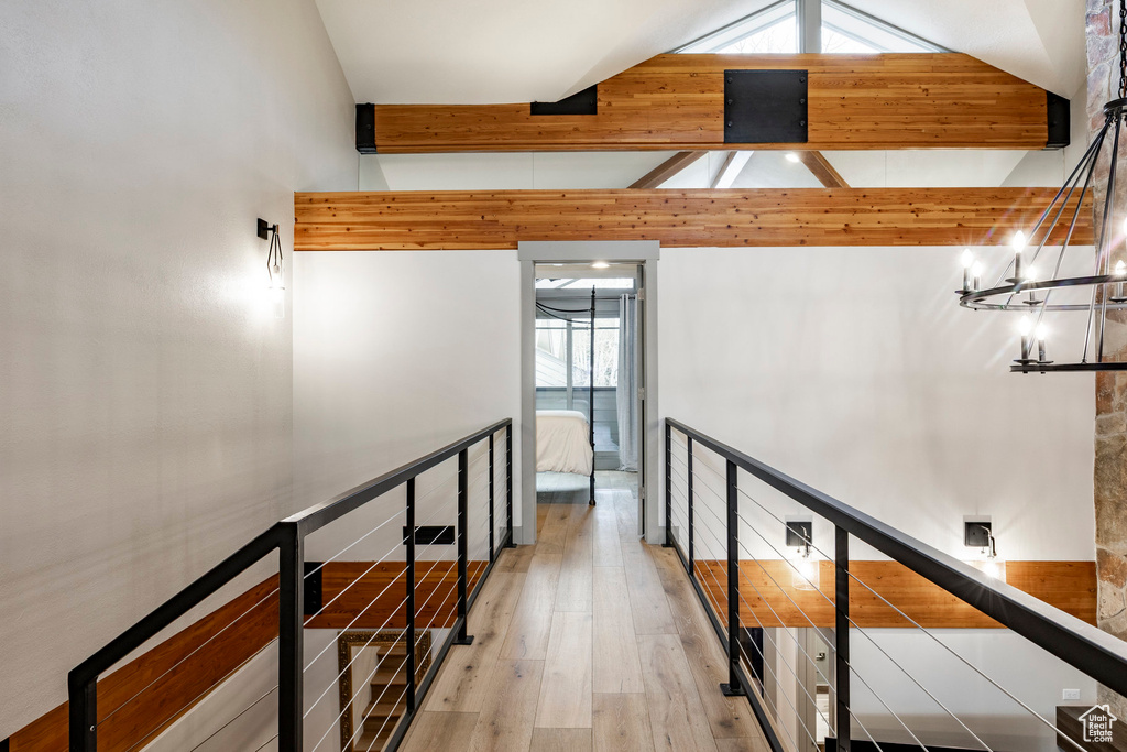 Hallway with lofted ceiling with beams, an upstairs landing, a notable chandelier, and wood finished floors