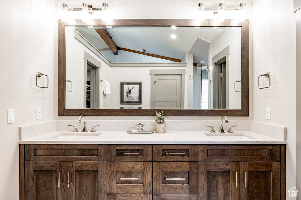 Bathroom with double vanity, vaulted ceiling, and a sink
