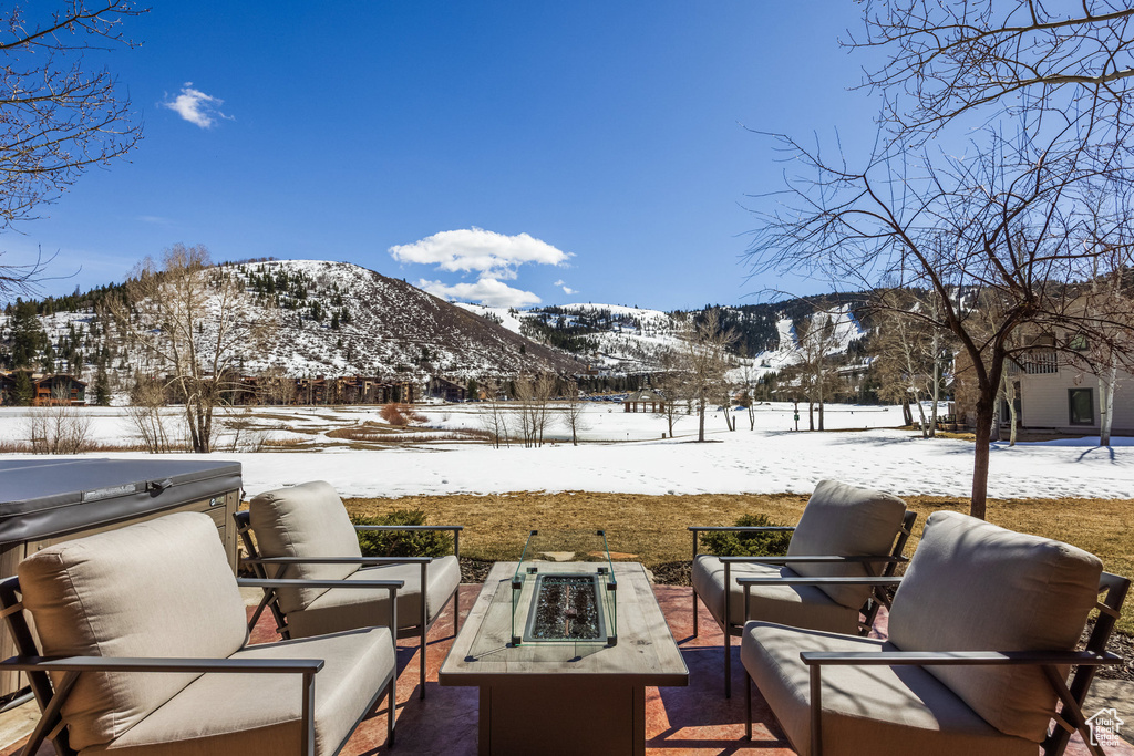 Snow covered patio with an outdoor living space with a fire pit, a mountain view, and fence