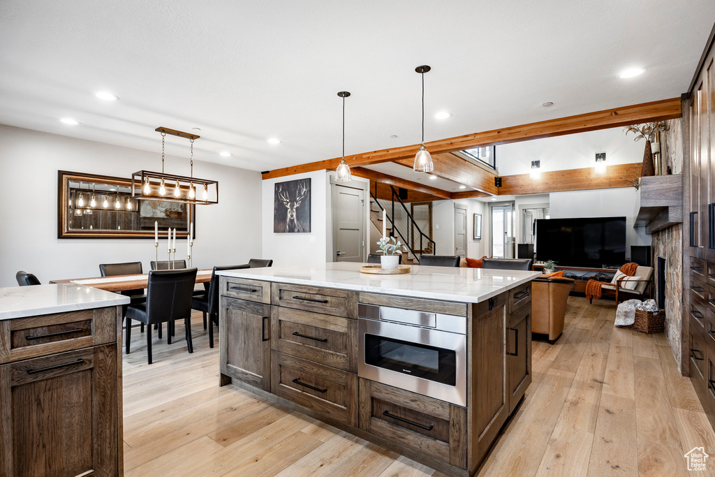 Kitchen featuring recessed lighting, a spacious island, light wood-style floors, built in microwave, and light stone counters