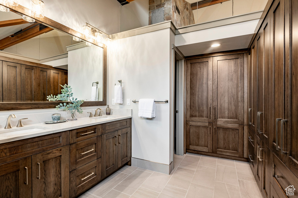 Full bathroom featuring double vanity, a sink, tile patterned flooring, and baseboards