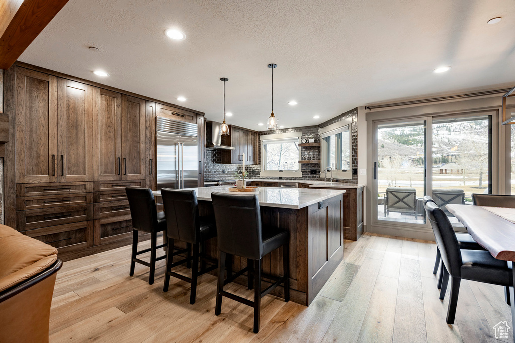 Kitchen featuring stainless steel built in fridge, light countertops, a center island, and a healthy amount of sunlight