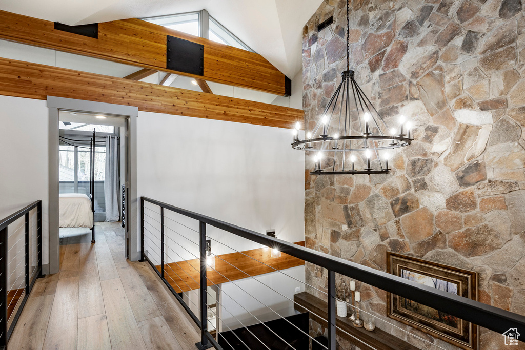 Hall featuring high vaulted ceiling, an upstairs landing, beam ceiling, an inviting chandelier, and wood-type flooring