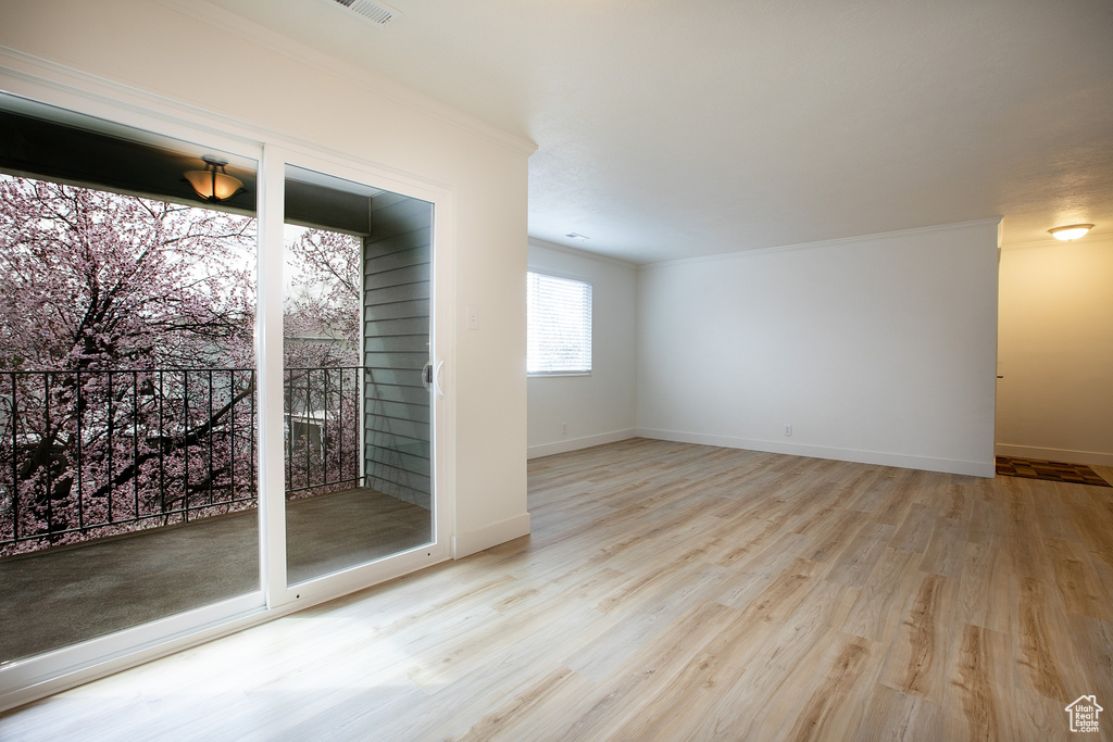 Empty room with ornamental molding, wood finished floors, and baseboards
