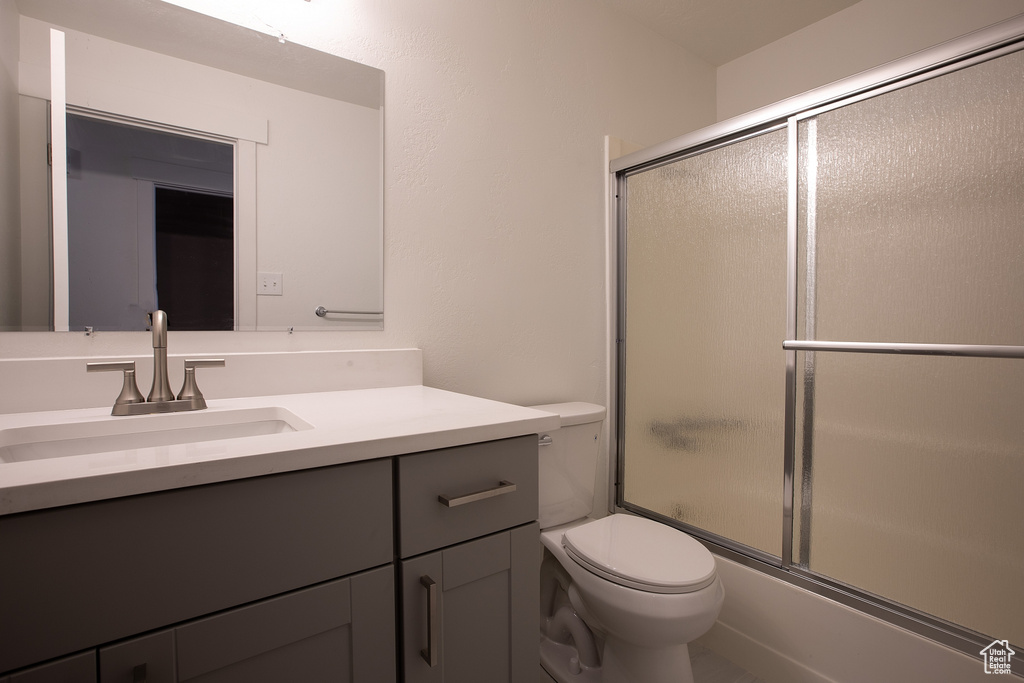 Bathroom featuring toilet, vanity, and shower / bath combination with glass door