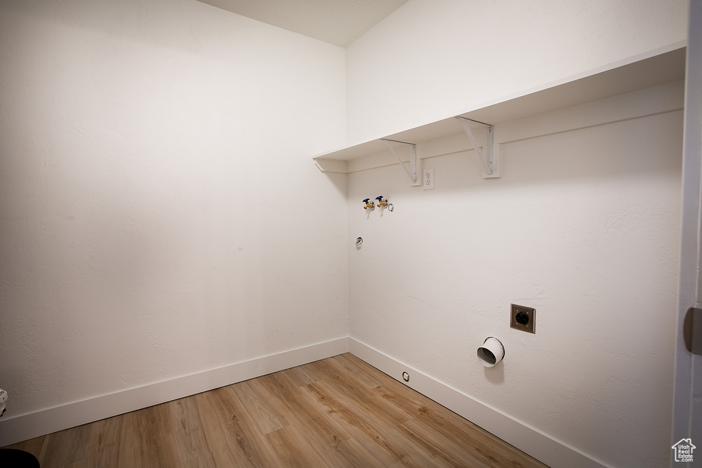 Washroom with gas dryer hookup, light wood-style flooring, baseboards, hookup for a washing machine, and hookup for an electric dryer
