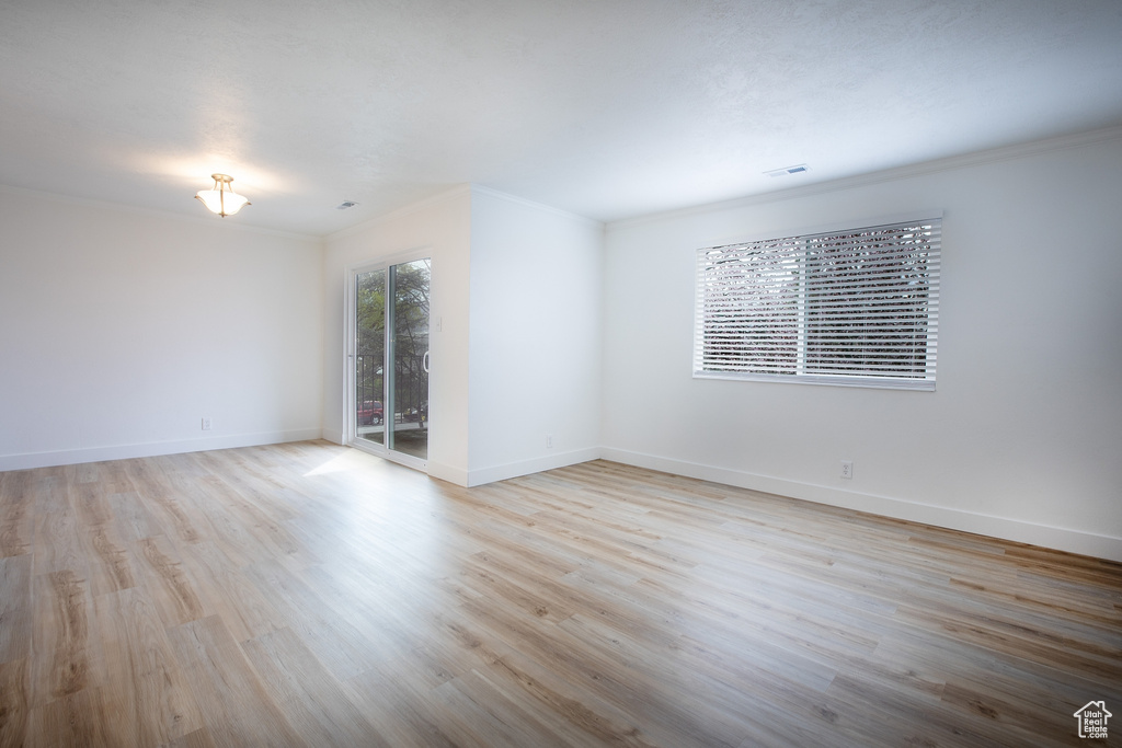 Empty room with wood finished floors, ornamental molding, and baseboards