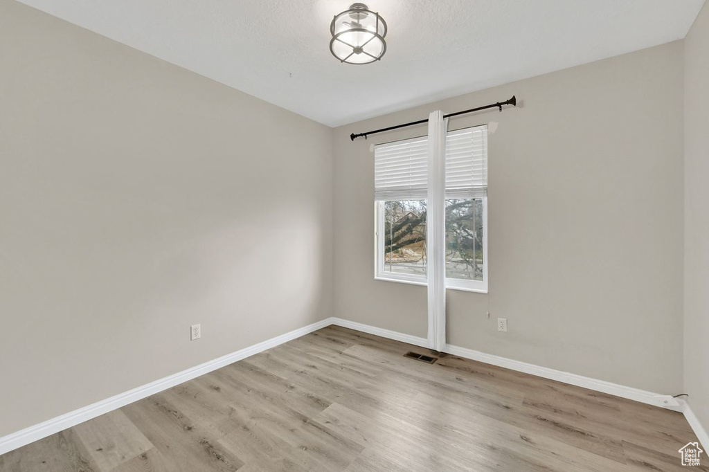 Spare room with wood finished floors, baseboards, and visible vents