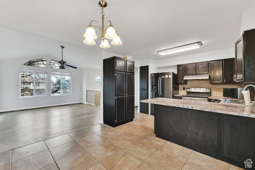 Kitchen featuring tasteful backsplash, under cabinet range hood, electric stove, a sink, and ceiling fan with notable chandelier