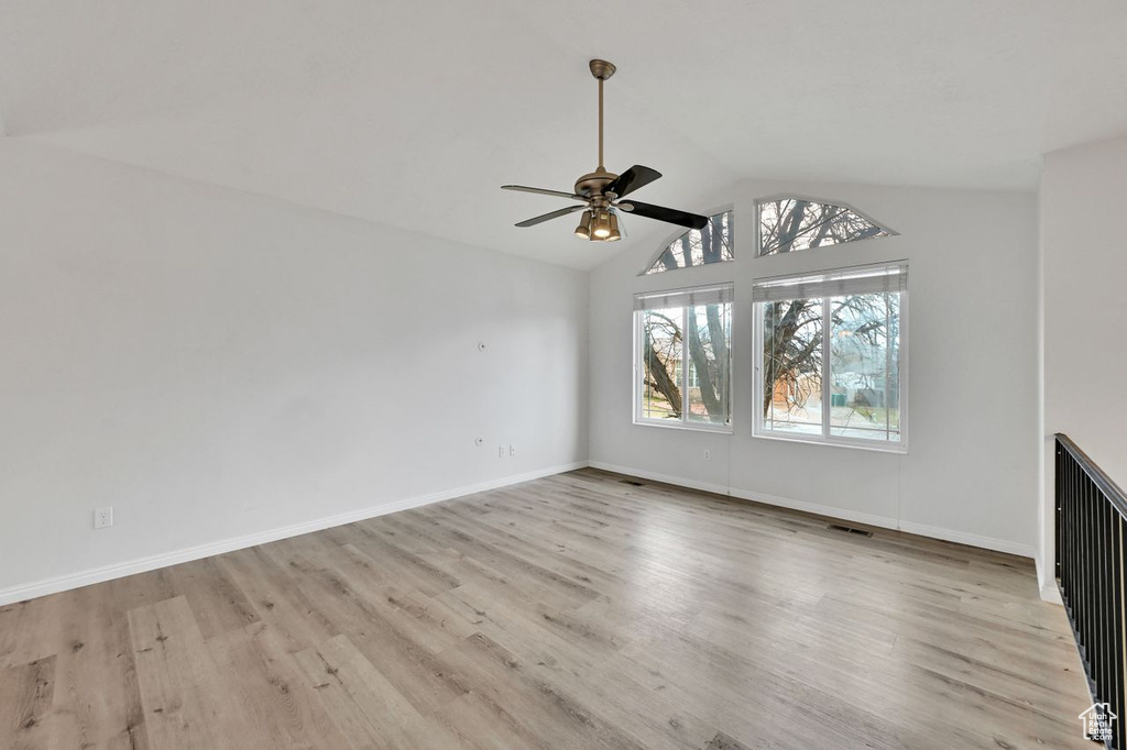 Unfurnished living room featuring visible vents, light wood finished floors, baseboards, ceiling fan, and lofted ceiling