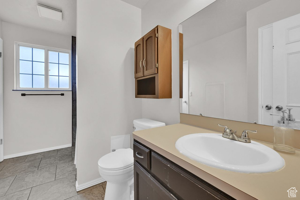 Bathroom with toilet, vanity, and baseboards