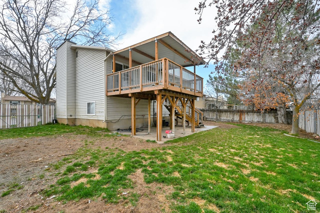 Rear view of house featuring a patio area, a chimney, a deck, a fenced backyard, and a yard