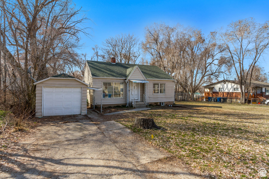 View of front of house featuring driveway, a chimney, a front lawn, entry steps, and a garage