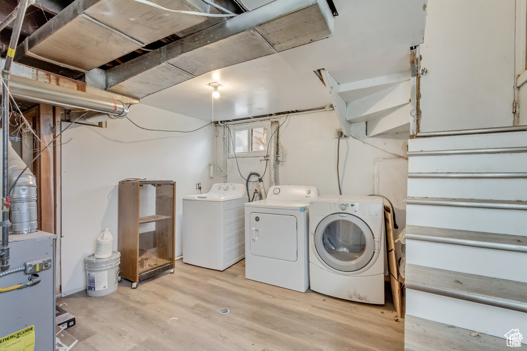 Laundry area with washing machine and dryer, laundry area, a heating unit, and light wood finished floors