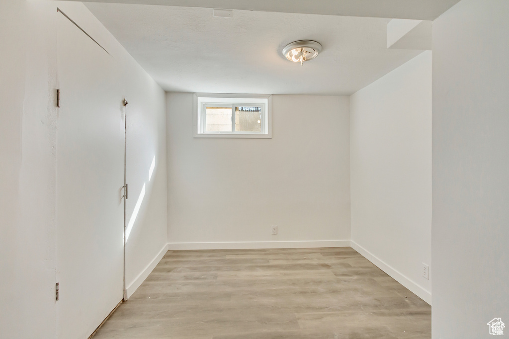 Basement with baseboards and light wood-style floors