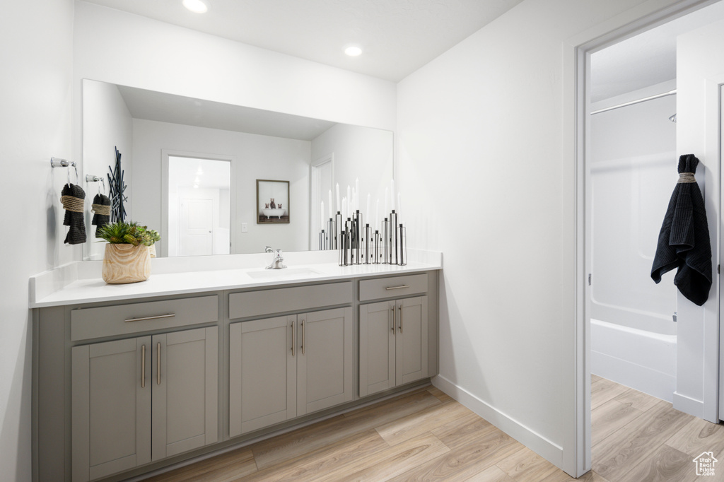 Full bathroom featuring recessed lighting, vanity, baseboards, and wood finished floors
