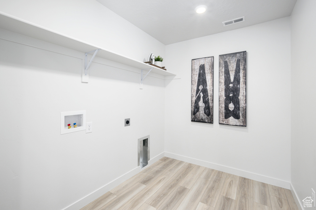 Clothes washing area featuring light wood-type flooring, baseboards, visible vents, laundry area, and washer hookup
