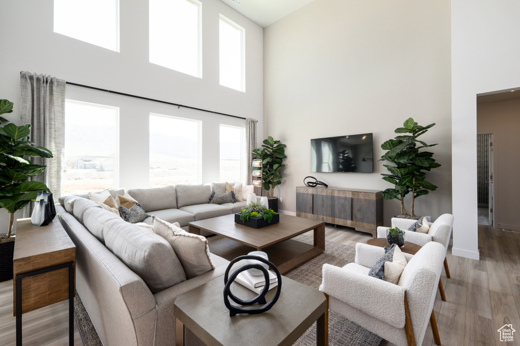 Living room with a high ceiling, baseboards, and light wood-type flooring