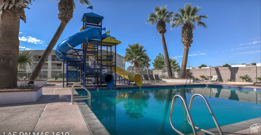 Pool featuring playground community, a water slide, and fence