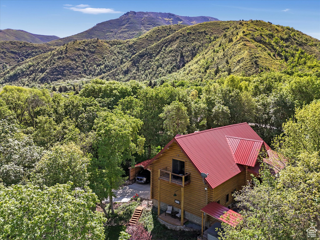 Aerial view of property and surrounding area featuring a heavily wooded area and a mountain backdrop