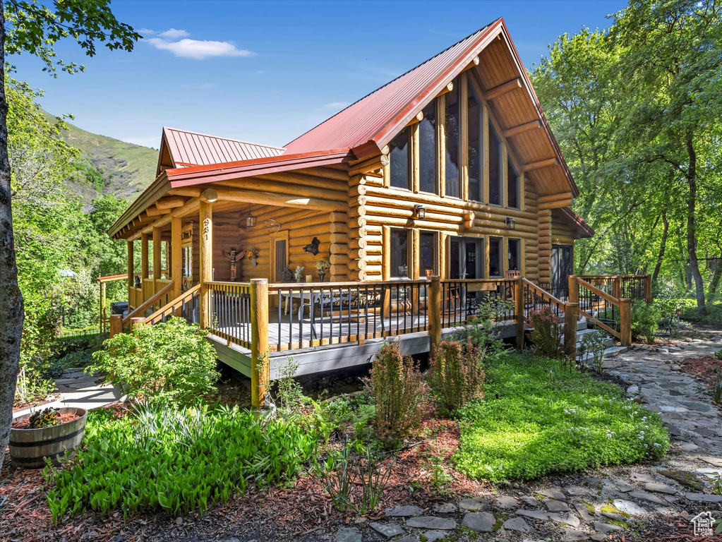 Back of house featuring log siding, metal roof, and a wooden deck
