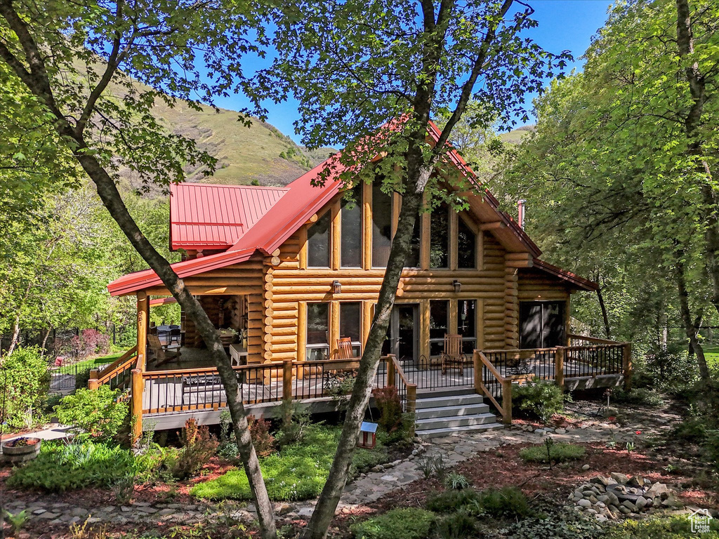 View of front of house featuring log exterior, a wooden deck, and metal roof