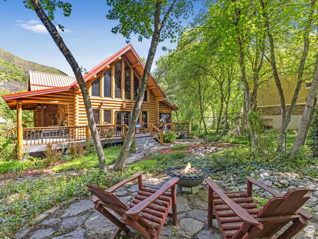 Rear view of house featuring a fire pit, log exterior, a wooden deck, and metal roof