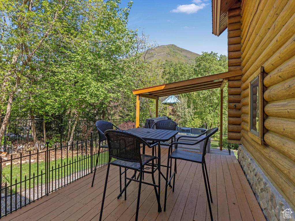 Wooden terrace featuring a mountain view, outdoor dining area, and fence