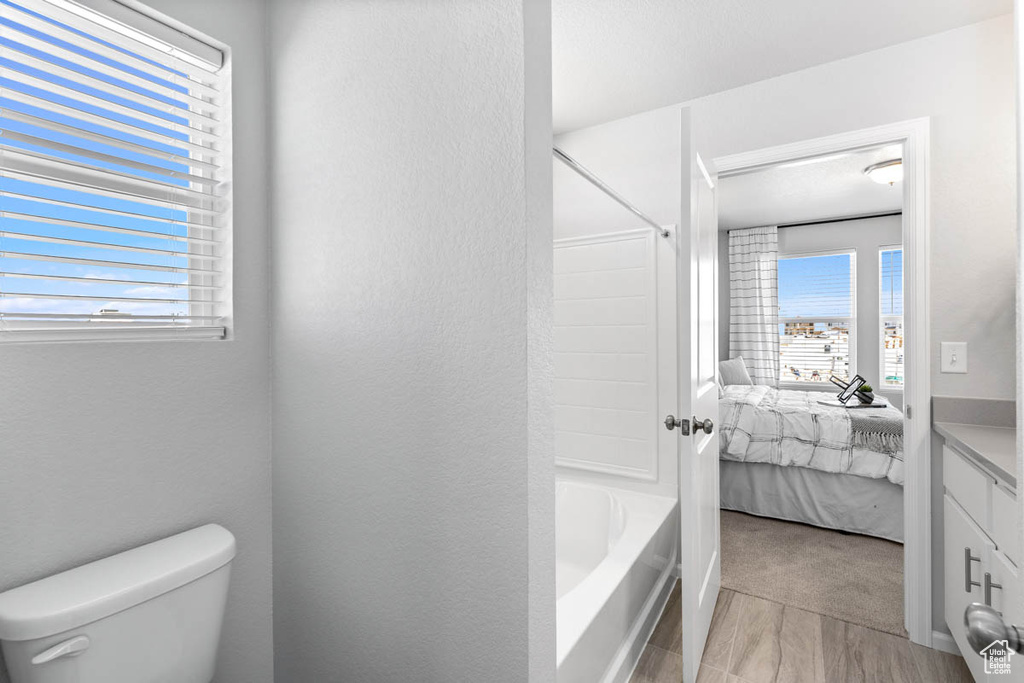 Bathroom featuring plenty of natural light, a textured wall, toilet, and ensuite bathroom