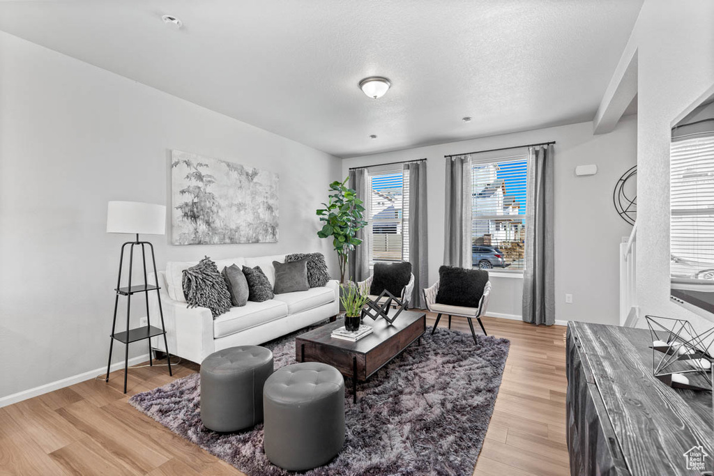 Living area featuring baseboards, light wood finished floors, and a textured ceiling