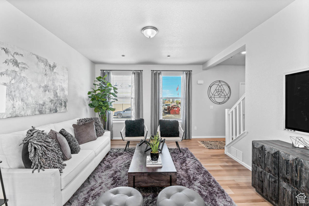 Living room featuring stairs, wood finished floors, and baseboards
